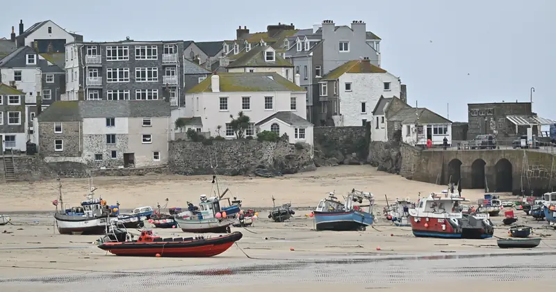 Charming view of St Ives harbour in England with fishing boats at low tide.