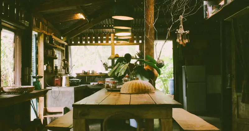 Inviting rustic kitchen interior featuring wooden furniture, natural lighting, and vibrant plants.